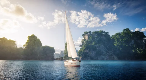 Sailboat beside tropical limestone cliffs