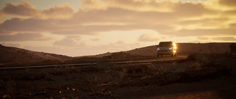 Van crossing an open landscape at sunset