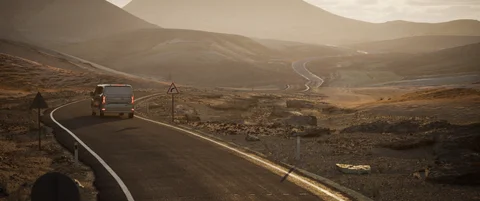 Vehicle following a winding road through open hills